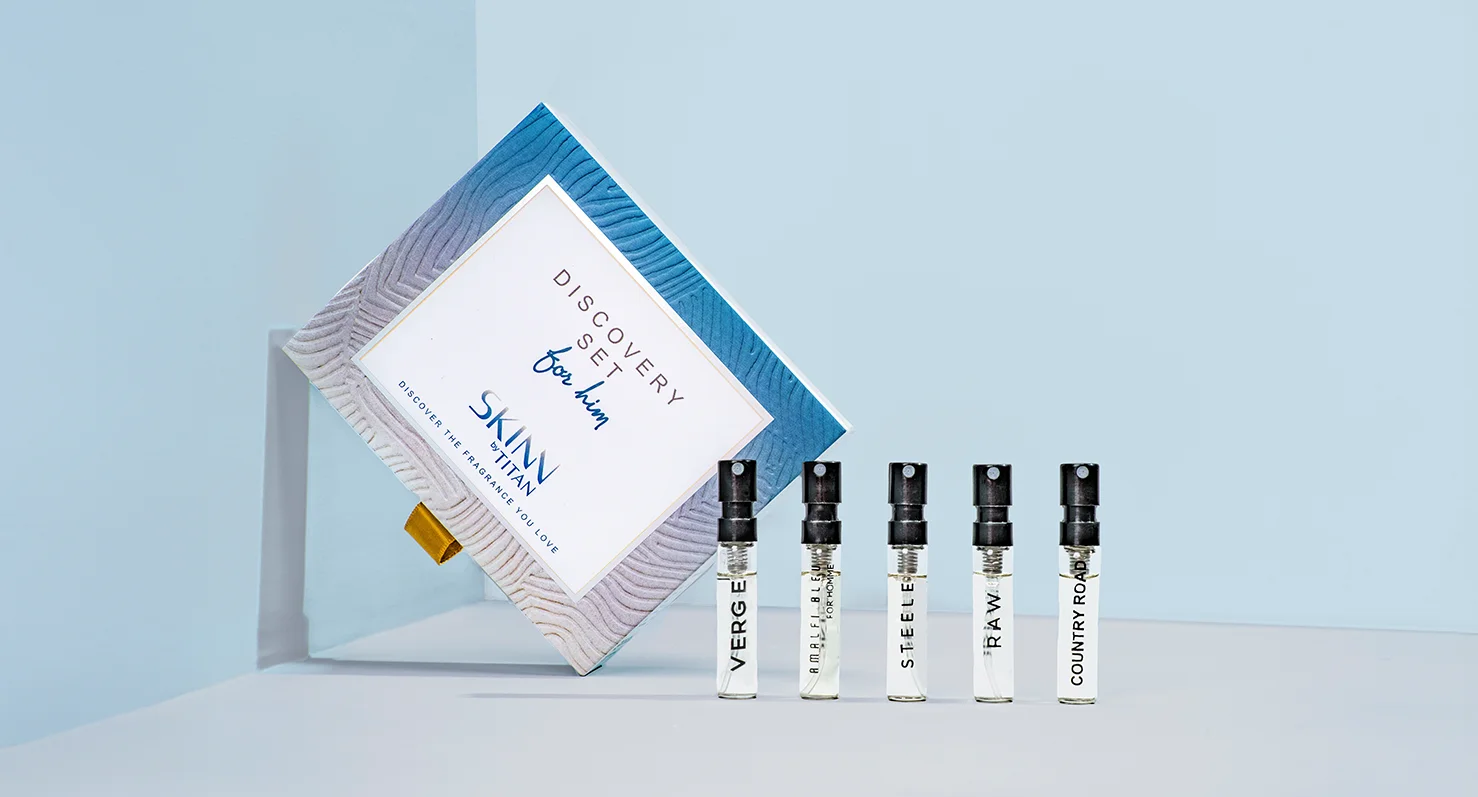 The SKINN by TITAN 'Discovery Set for him' in its blue-patterned box, with the five men's perfume samples lined up: Verge, Amalfi Blu, Steele, Raw, and Country Road.