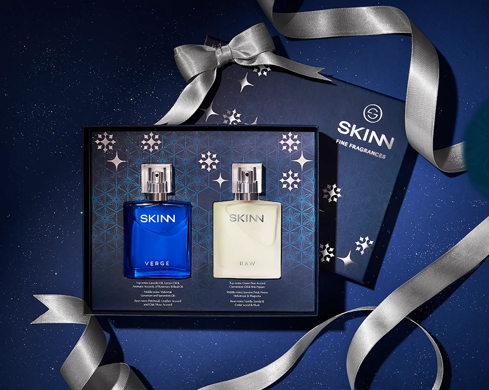 A festive Titan Skinn men's fragrance gift set featuring two signature scents, Verge and Raw, from the 'art of the gift' collection. The premium dark blue packaging, designed by Kern Culture with silver snowflake motifs and a silver ribbon, presents the woody notes of Verge and the fresh citrus of Raw as a perfect luxury gift for the holiday season.