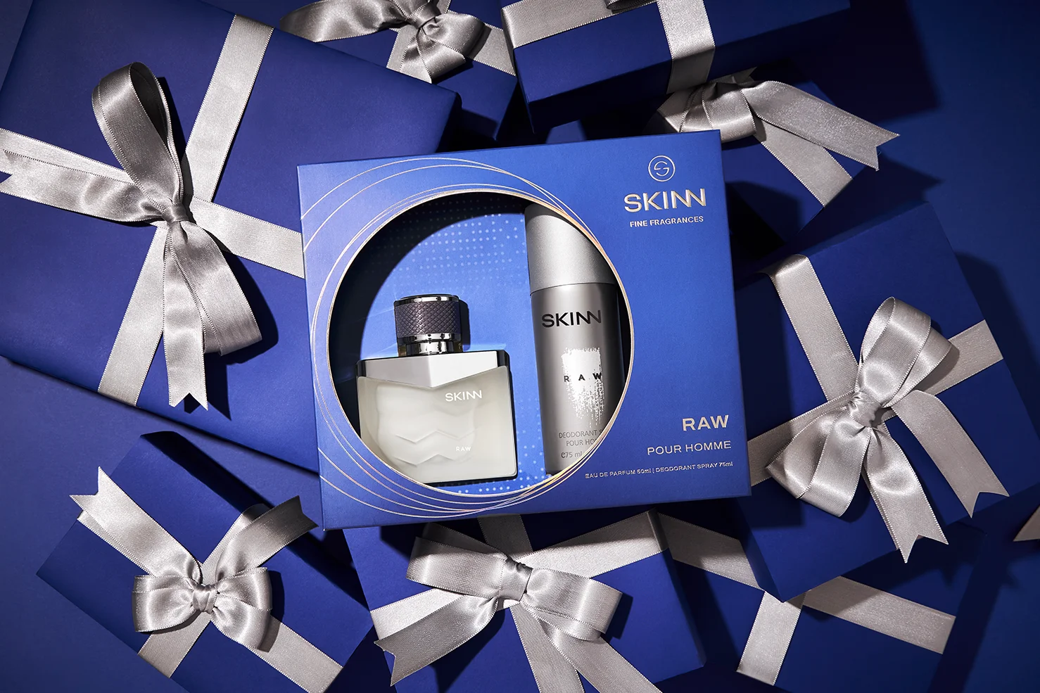 The final Titan Skinn Raw men's fragrance coffret, a result of Kern Culture's meticulous packaging design and art direction. The gift set, containing a 50ml EDP and deodorant with fresh citrus and warm woody notes, is elegantly photographed amongst deep blue gift boxes with silver ribbons, perfectly capturing the festive 'art of the gift' campaign theme.