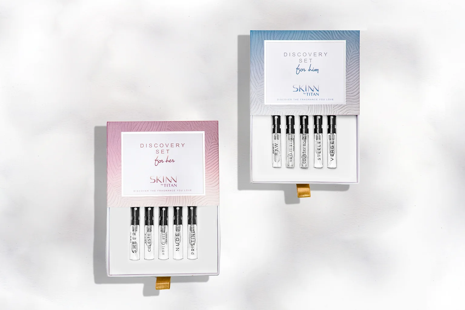 The SKINN by TITAN 'Discovery Set for her' in its pink-patterned box, with the five women's perfume samples displayed on a block: Pristine, Celeste, Amalfi Blu, Nude, and Sheer.